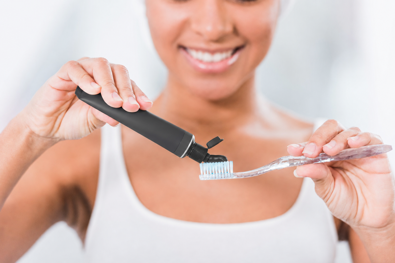 Woman using charcoal toothpaste for teeth whitening